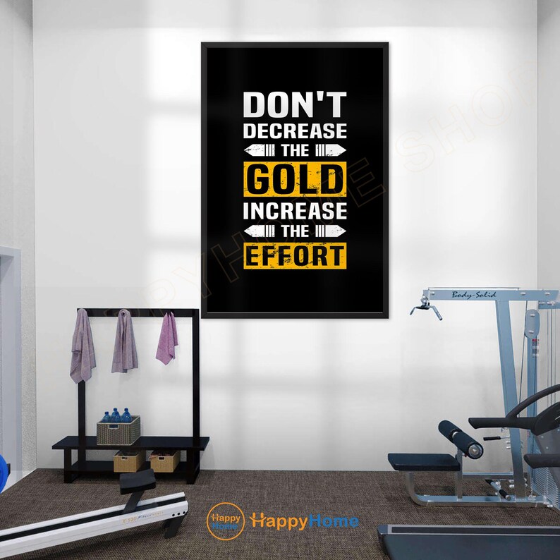 May include: A motivational poster with a black background and white and gold text that reads "DON'T DECREASE THE GOLD INCREASE THE EFFORT." The poster is framed and hangs on a white wall in a gym setting.