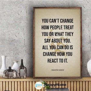 Puede incluir: Una cita motivacional de Mahatma Gandhi impresa en un fondo beige con un marco de madera marrón. La cita dice: "No puedes cambiar cómo la gente te trata o lo que dicen de ti. Todo lo que puedes hacer es cambiar cómo reaccionas."