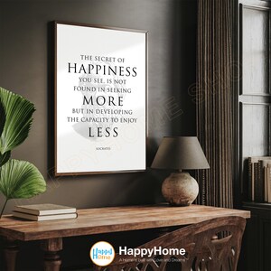 May include: A black and white framed print with a quote by Socrates: "The secret of happiness you see, is not found in seeking more but in developing the capacity to enjoy less."