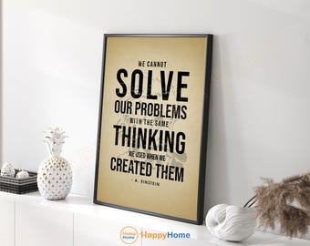 May include: A framed print with a black frame and a tan background. The print features the quote "WE CANNOT SOLVE OUR PROBLEMS WITH THE SAME THINKING WE USED WHEN WE CREATED THEM" by A. Einstein in bold black text. Decorative items are on the white shelf.
