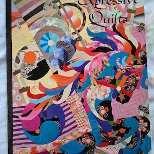 May include: A book titled "Expressive Quilts" with a vibrant patchwork design. The cover art depicts a horse-like form made from diverse fabric patterns in blue, pink, orange, and purple. The author's name, Kumiko Sudo, is also displayed on the cover.