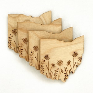 Puede incluir: Conjunto de cuatro posavasos de madera con un dise&ntilde;o grabado con l&aacute;ser del estado de Ohio con un patr&oacute;n floral. Los posavasos est&aacute;n hechos de madera marr&oacute;n claro y tienen un acabado natural.