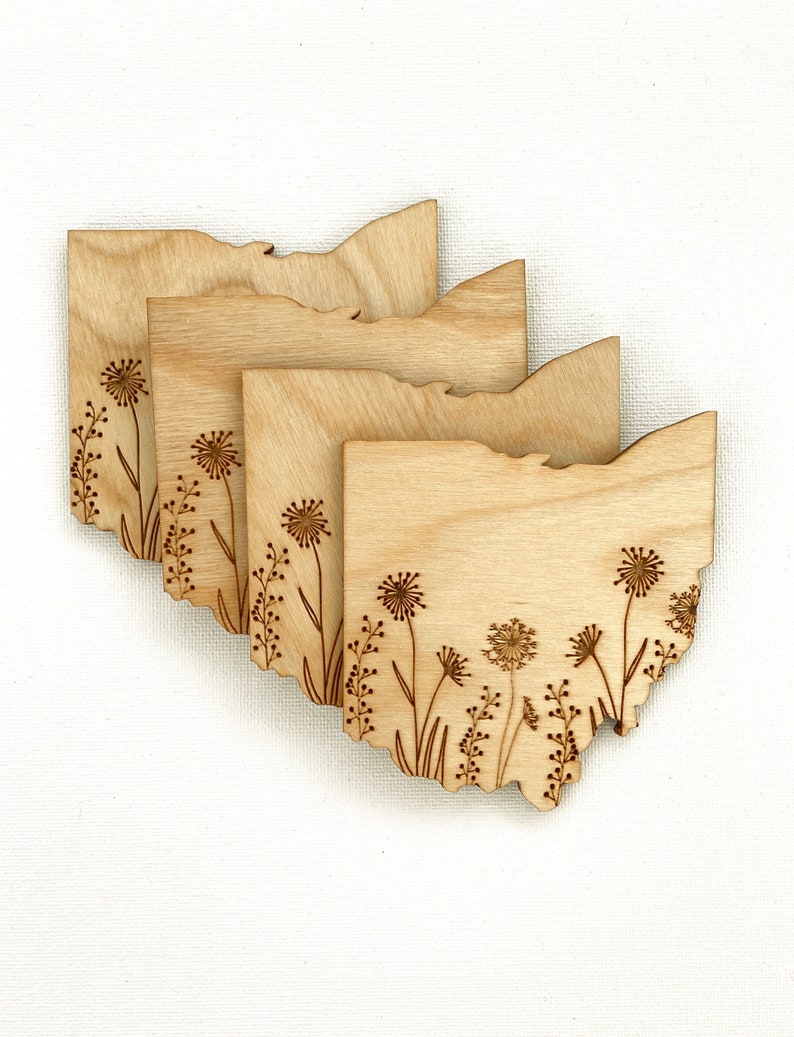 Puede incluir: Conjunto de cuatro posavasos de madera con un dise&ntilde;o grabado con l&aacute;ser del estado de Ohio con un patr&oacute;n floral. Los posavasos est&aacute;n hechos de madera marr&oacute;n claro y tienen un acabado natural.
