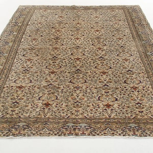 K&ouml;nnte beinhalten: Ein beiger Teppich mit Blumenmuster und einem Rand. Der Teppich hat einen abgenutzten Look und ist aus Wolle.