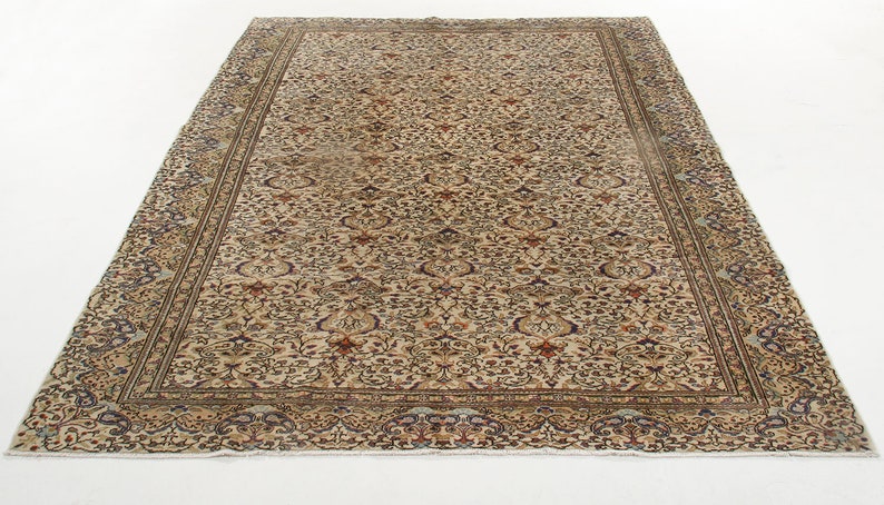 K&ouml;nnte beinhalten: Ein beiger Teppich mit Blumenmuster und einem Rand. Der Teppich hat einen abgenutzten Look und ist aus Wolle.