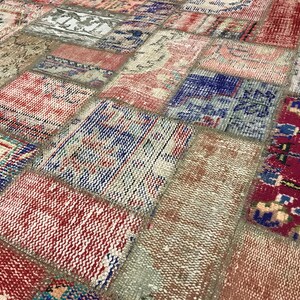 Puede incluir: Primer plano de una alfombra patchwork con una variedad de colores y patrones. La alfombra presenta parches rectangulares y cuadrados en tonos de rojo, azul, beige y crema. El dise&ntilde;o tiene un aspecto vintage y desgastado.