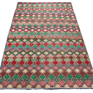 May include: A vintage rug with a geometric pattern of colorful diamonds in shades of pink, red, green, blue, and brown. The rug has a faded, distressed look, giving it a unique and antique feel.