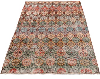 May include: A vintage rug with a geometric pattern in shades of red, orange, green, blue, and beige. The rug has a distressed look and is made of wool.