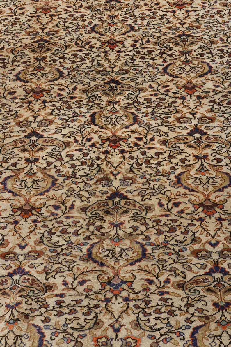 K&ouml;nnte beinhalten: Ein beiger Teppich mit einem detaillierten Blumenmuster in Braun-, Rot-, Blau- und Wei&szlig;t&ouml;nen.
