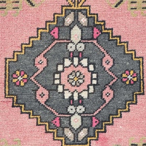 Pode incluir: Um tapete rosa com um design geom&eacute;trico em preto e branco. O tapete tem um medalh&atilde;o central com um padr&atilde;o floral.
