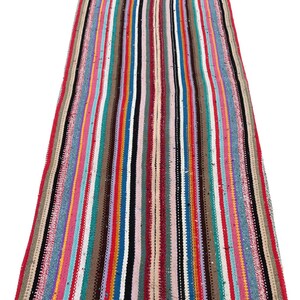 May include: A colorful striped rug with a variety of colors, including red, blue, green, and yellow. The rug is made of woven fabric and has a long, rectangular shape.