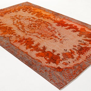 Könnte beinhalten: Ein Vintage-Teppich in Orange und Creme mit einem floralen Muster. Der Teppich hat einen verblassten Look und eine abgenutzte Textur.
