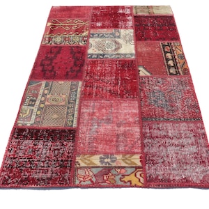May include: A red patchwork rug with a variety of patterns and designs. The rug is made from recycled materials and has a distressed look.