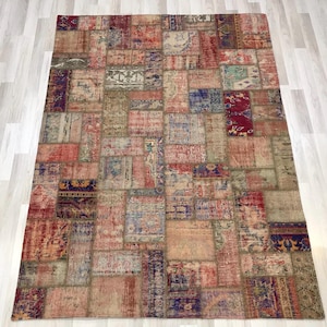 May include: A large, rectangular patchwork rug with a vintage aesthetic. The rug is composed of numerous rectangular and square patches in various colors, including red, blue, beige, and green. The patches feature intricate patterns and textures, creating a unique and eclectic design.