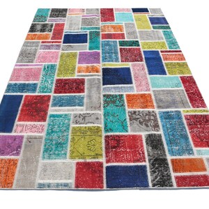Op de afbeelding: Een kleurrijk patchwork tapijt met een verscheidenheid aan kleuren en patronen, waaronder rood, blauw, groen, geel en oranje. Het tapijt is gemaakt van gerecyclede materialen en heeft een unieke, handgemaakte uitstraling.