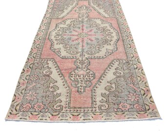 Puede incluir: Una alfombra vintage de color rosa y gris con un patrón floral. La alfombra tiene un aspecto desgastado y está hecha de lana.
