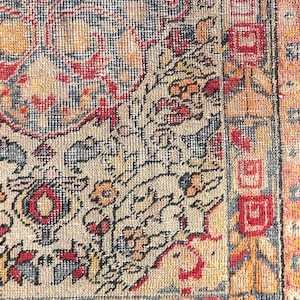 May include: A vintage rug with a detailed floral pattern in shades of red, orange, blue, and beige. The rug has a fringe border and is woven with a fine texture.