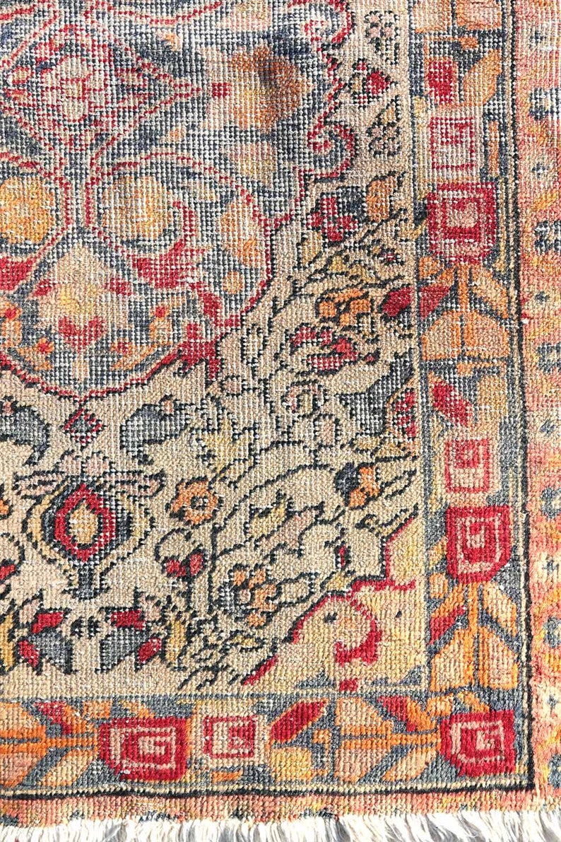 May include: A vintage rug with a detailed floral pattern in shades of red, orange, blue, and beige. The rug has a fringe border and is woven with a fine texture.