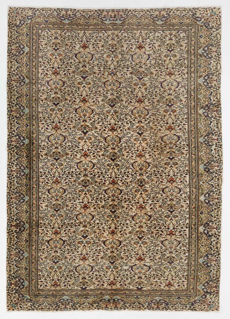 K&ouml;nnte beinhalten: Ein Vintage-Teppich mit cremefarbenem Hintergrund und komplizierten floralen Mustern in Braun-, Blau- und Rott&ouml;nen. Der Teppich hat einen Rand mit einem sich wiederholenden Muster.