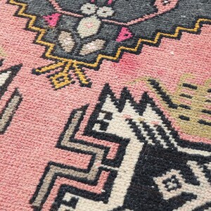 Pode incluir: Um tapete rosa com um padr&atilde;o geom&eacute;trico em preto, branco e amarelo. O padr&atilde;o apresenta um design de animal estilizado.