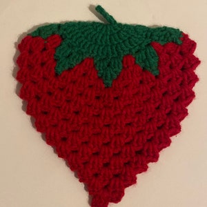 Puede incluir: Un salvamanteles hecho a mano de ganchillo con forma de fresa. El salvamanteles es principalmente rojo con un tallo y hojas verdes. Las puntadas de ganchillo crean una superficie texturizada, que se asemeja a la textura de una fresa real. Este accesorio de cocina está diseñado para proteger las superficies del calor.