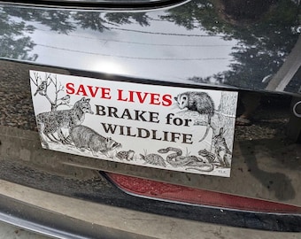 May include: A rectangular bumper sticker with the text "SAVE LIVES BRAKE for WILDLIFE" in red and black. The sticker features illustrations of various animals, including a wolf, raccoon, opossum, and snake, in black and white.