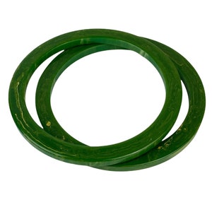 May include: Two green plastic bangle bracelets with a marbled pattern. The bracelets are stacked on top of each other.