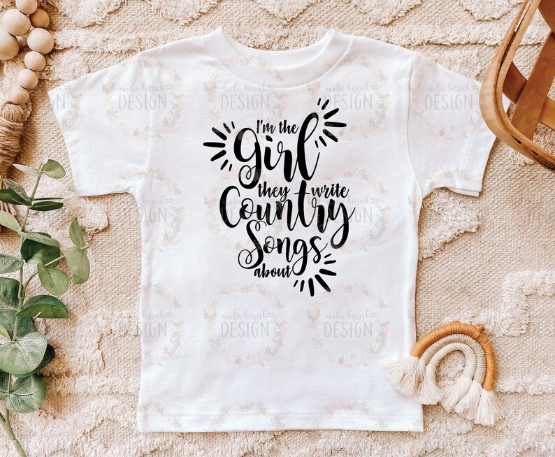Puede incluir: Camiseta blanca con texto negro que dice "Soy la chica de la que escriben canciones country".