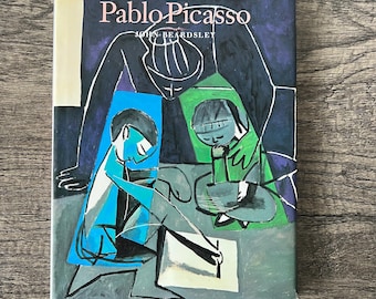 May include: A book titled "First Impressions Pablo Picasso" by John Beardsley. The cover features a colorful abstract painting of two figures, one in blue and one in green, with a black outline.