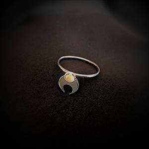 Könnte beinhalten: Ein silberner Ring mit einem Halbmond-Design und einem kleinen, runden, gelben Edelstein in der Mitte.