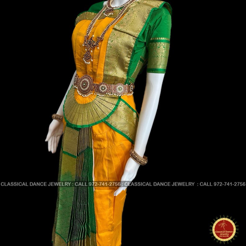 May include: A traditional Indian classical dance costume. The outfit features a yellow skirt and bodice with green and gold accents. The costume includes ornate jewelry and a decorative belt. The sleeves are short and green. The text on the image says "CLASSICAL DANCE JEWELRY".