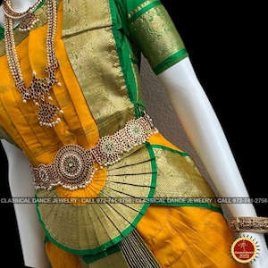 May include: A traditional Indian dance costume in yellow and green, featuring ornate gold jewelry with red and green accents. The costume includes a necklace, waist belt, and arm cuffs. The image also includes the text "CLASSICAL DANCE JEWELRY".