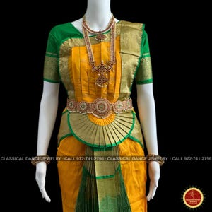 May include: A traditional Indian classical dance costume. The ensemble features a yellow and green sari with gold accents, a matching belt, and ornate jewelry. The costume is displayed on a mannequin against a black background. The text "CLASSICAL DANCE JEWELRY" is visible.