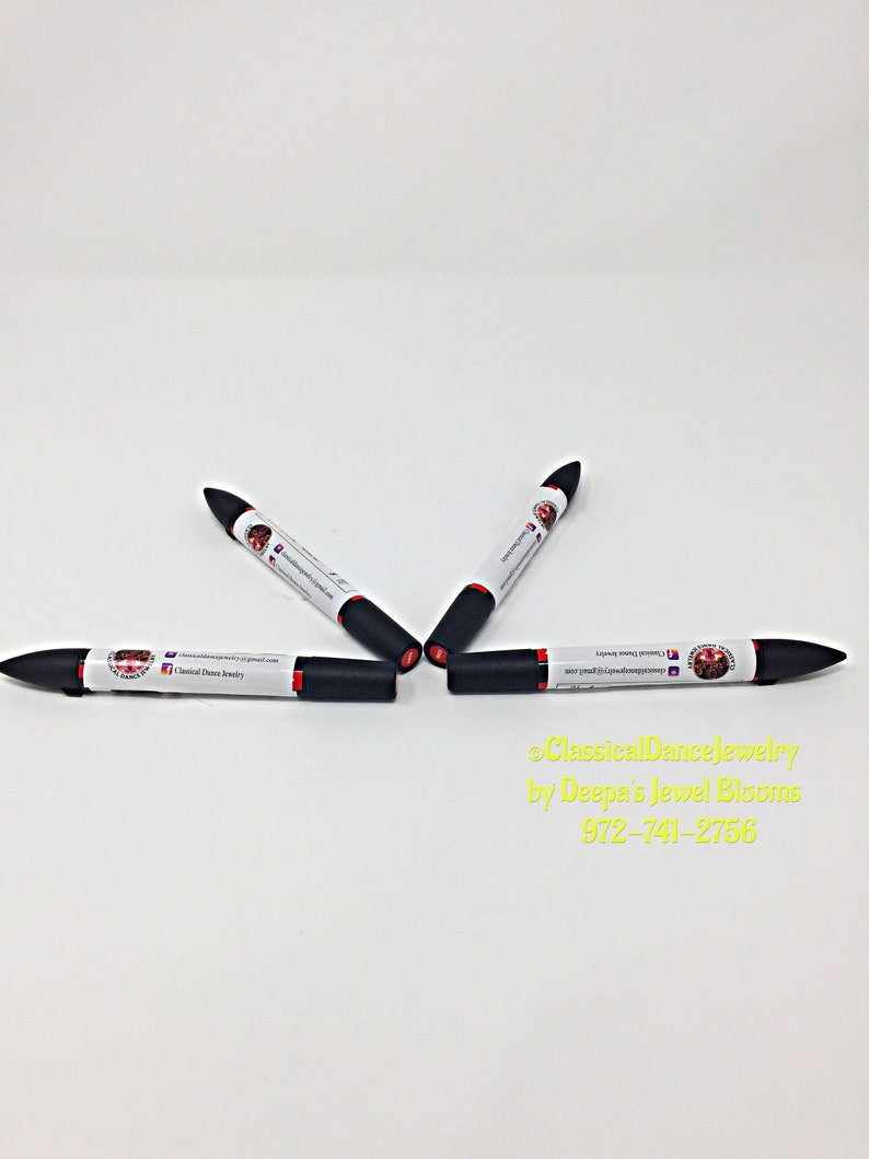 May include: Four black and red dual-tip markers on a white background. Each marker features a white label with text and a logo. The image also includes yellow text: "ClassicalDanceJewelry by Deepa's Jewel Blooms".