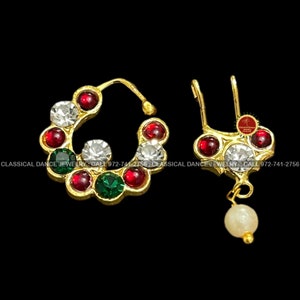May include: A pair of gold nose rings with red, green, and white stones. The ring on the left is a hoop with a dangling pearl on the right.