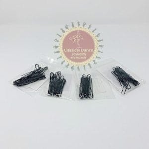 May include: Four clear plastic bags containing black bobby pins. The bags are on a white surface. The bags are labeled "Classical Dance Jewelry 972-741-2756".