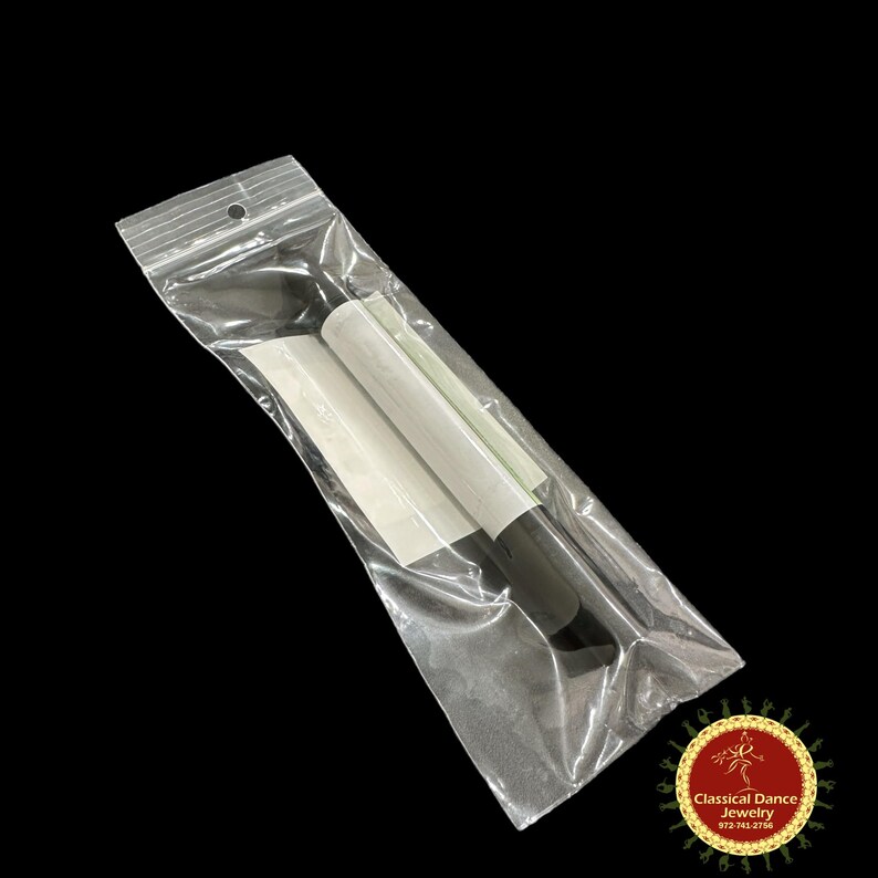 May include: A transparent plastic bag containing white and black dance accessories. The bag is sealed at the top with a small hole for hanging. The accessories appear to be for a dance instrument.