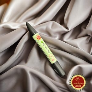 May include: A black pen with a green and white label featuring the text "972-741-2756" and "classicaldancejewelry.net". The pen has a conical tip and is set against a grey, silky background. A circular logo is visible.