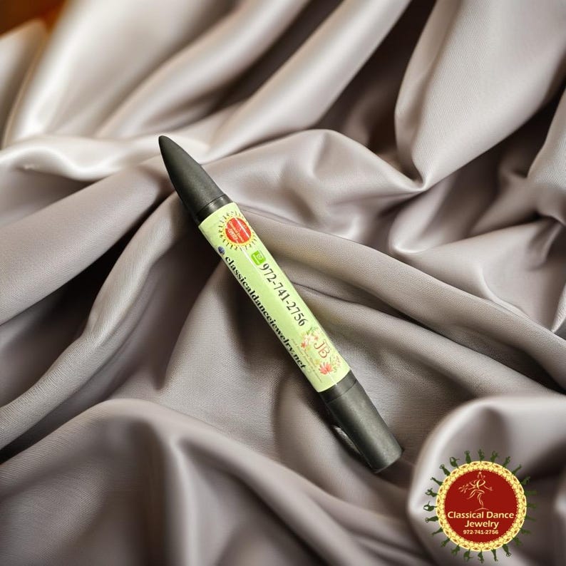 May include: A black pen with a green and white label featuring the text "972-741-2756" and "classicaldancejewelry.net". The pen has a conical tip and is set against a grey, silky background. A circular logo is visible.