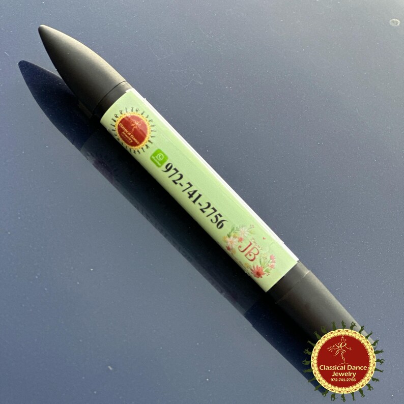 May include: A black and green lipstick-shaped product with a light green label. The label features the phone number 972-741-2756, floral designs, and the initials "JB". The product has a logo with the text "Classical Dance Jewelry".