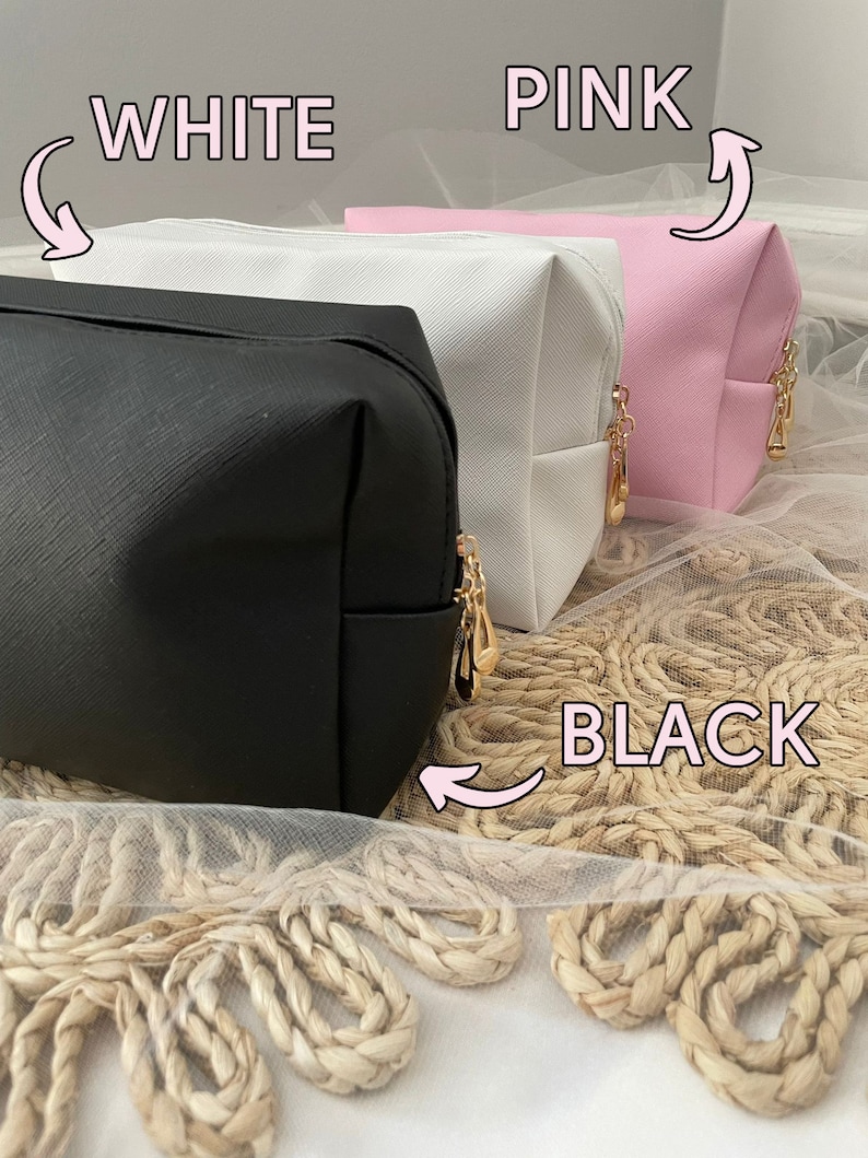 K&ouml;nnte beinhalten: Drei Kosmetiktaschen in Schwarz, Wei&szlig; und Rosa. Die Taschen sind aus einem strukturierten Material gefertigt und haben goldene Rei&szlig;verschl&uuml;sse. Die Taschen liegen auf einer gewebten Oberfl&auml;che.