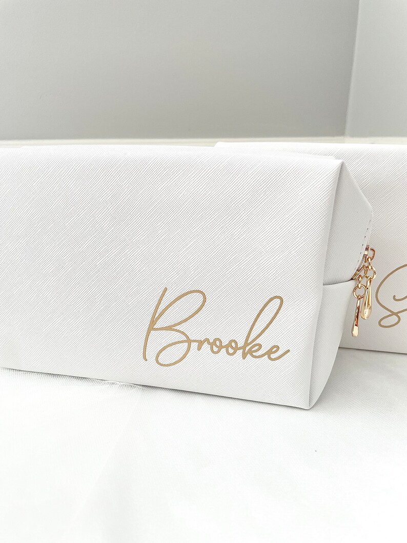 May include: White zippered makeup bag with a gold zipper pull and the name "Brooke" written in gold script.