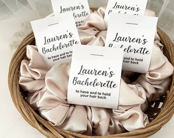 May include: A basket of beige satin scrunchies with white labels that say "Lauren's Bachelorette" and "to have and to hold your hair back".