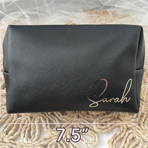 K&ouml;nnte beinhalten: Schwarze, gezippte Kosmetiktasche mit goldener Aufschrift "Sarah". Die Tasche misst 19 cm in der Breite, 13 cm in der H&ouml;he und 5 cm in der Tiefe.