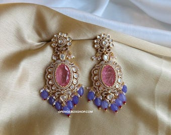 Puede incluir: Un par de pendientes de oro con piedras rosas y blancas y cuentas azules. Los pendientes tienen un diseño floral en la parte superior y una piedra rosa grande en el centro.