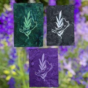 May include: Three rectangular fabric patches with pinked edges. Each patch features a white embroidered design of a jawbone intertwined with leaves. The patches are colored in deep green, dark gray, and purple, each with a mottled texture.