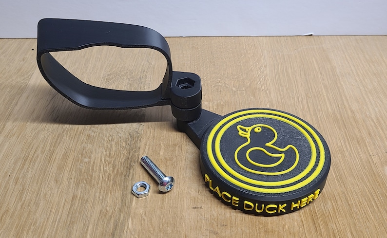 May include: Black 3D printed duck holder with a yellow rubber duck and the text "Place Duck Here".