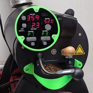 May include: A black coffee roaster with a green control panel. The panel displays the bean temperature at 359 degrees, the drum temperature at 223 degrees, the time at 5:20, and the fan speed at F3. The roaster has a wooden handle and a bean hopper.