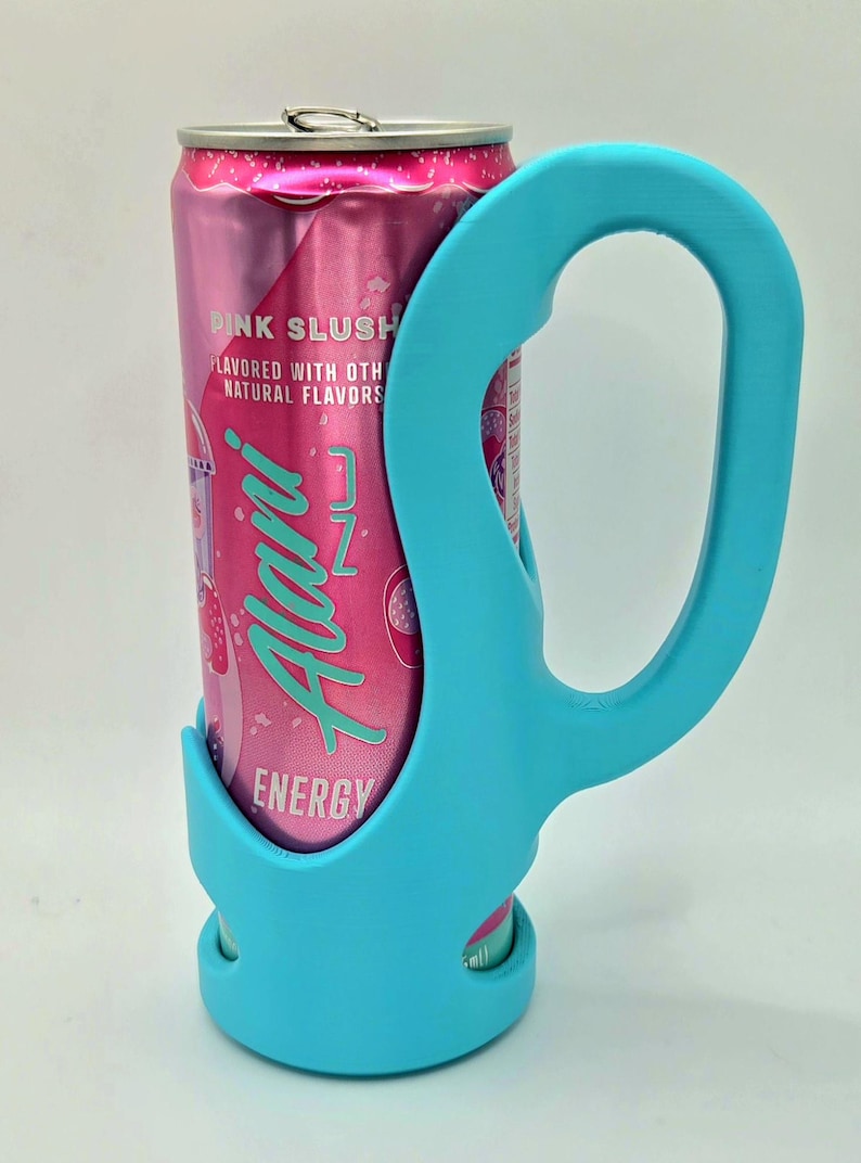 Op de afbeelding: Een roze energiedrankblikje met de tekst "Pink Slush" en "Alani Nu Energy" wordt vastgehouden door een helderblauwe blikjeshouder. De houder heeft een handvat.