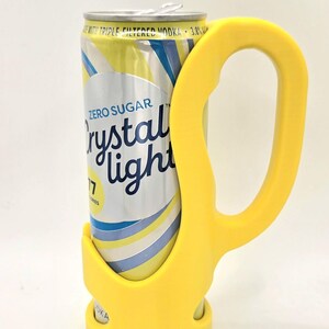 Op de afbeelding: Een gele blikhouder met handvat, ontworpen om een blikje Crystal Light in te houden. Het blikje is zilverkleurig met gele en blauwe strepen en de woorden "Zero Sugar Crystal Light" erop gedrukt. Op het blikje staat ook "with triple filtered vodka 3.8%".